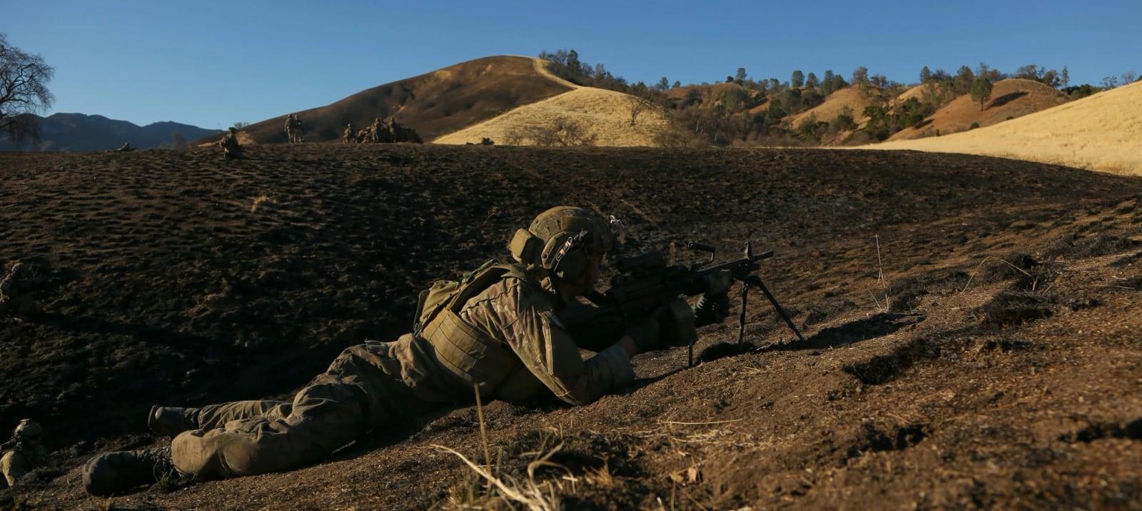 U.S. Army Ranger providing security with a bipod-mounted Mk46 machine gun on a hillside