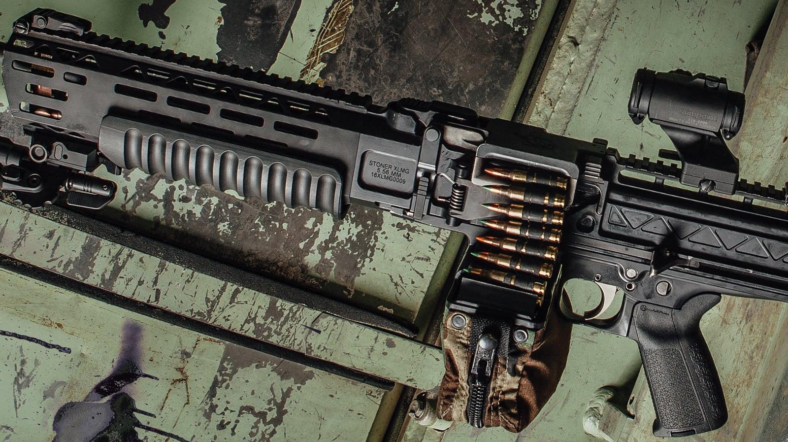Close view of the LAMG receiver, feed tray and linked ammunition on a weathered green surface