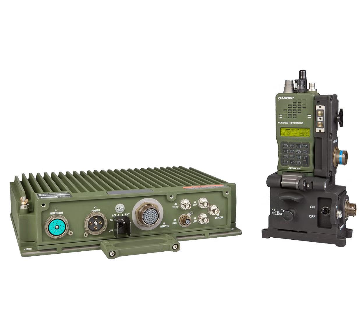 A finned green vehicular amplifier beside a handheld radio seated in its remote control dock