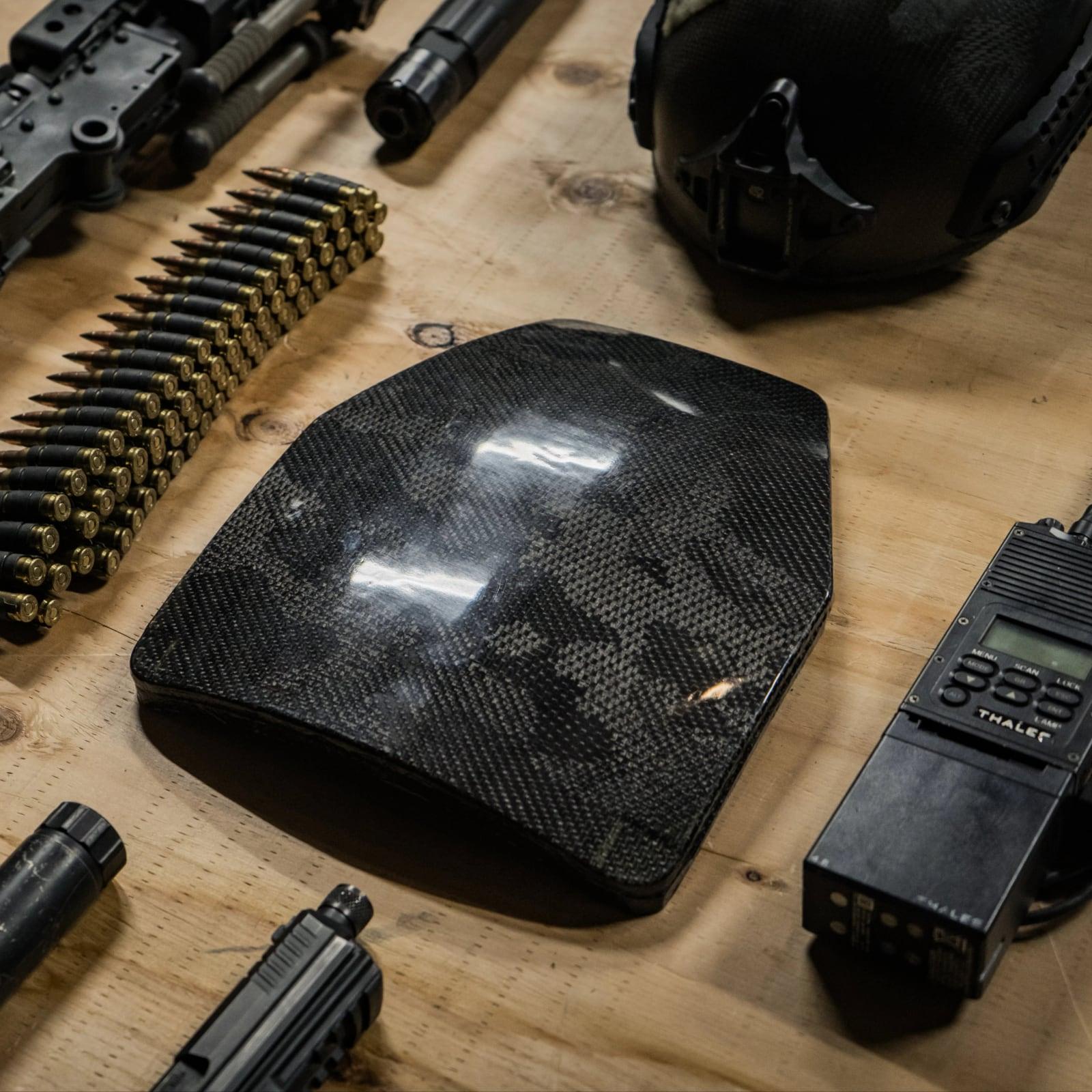 Carbon-finish plate laid out with a helmet, radio and belted ammunition