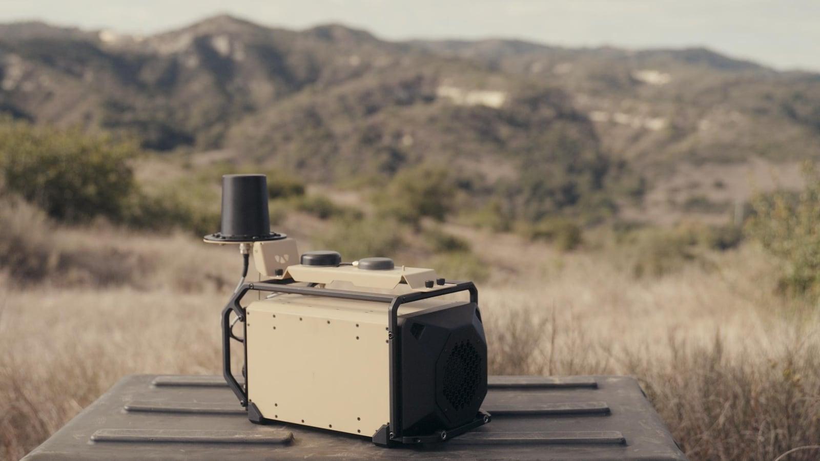 A cream and black EW unit with a tall antenna on a platform in an arid landscape